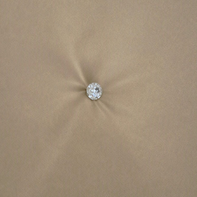 A single round clear crystal or gemstone stud with a silver-toned setting, centered on a soft, beige fabric background. Swatch of Monaco Crystal in Mystery - COMOK-MYS-PUM COMOQ-MYS-PUM THMOK-MYS-PUM