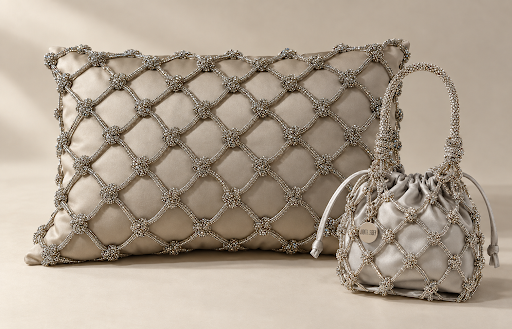 A silver satin pillow and matching drawstring handbag, both decorated with a diamond-shaped beaded net pattern, displayed on a neutral beige background.